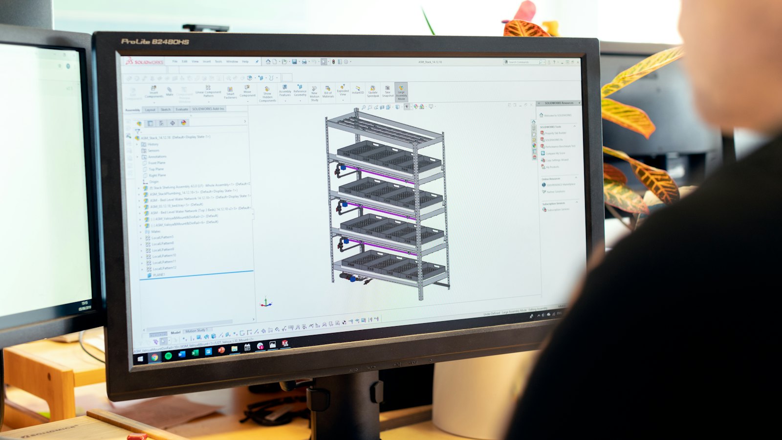 A 3D model of a racked assembly with pipework open in design software on a monitor.
