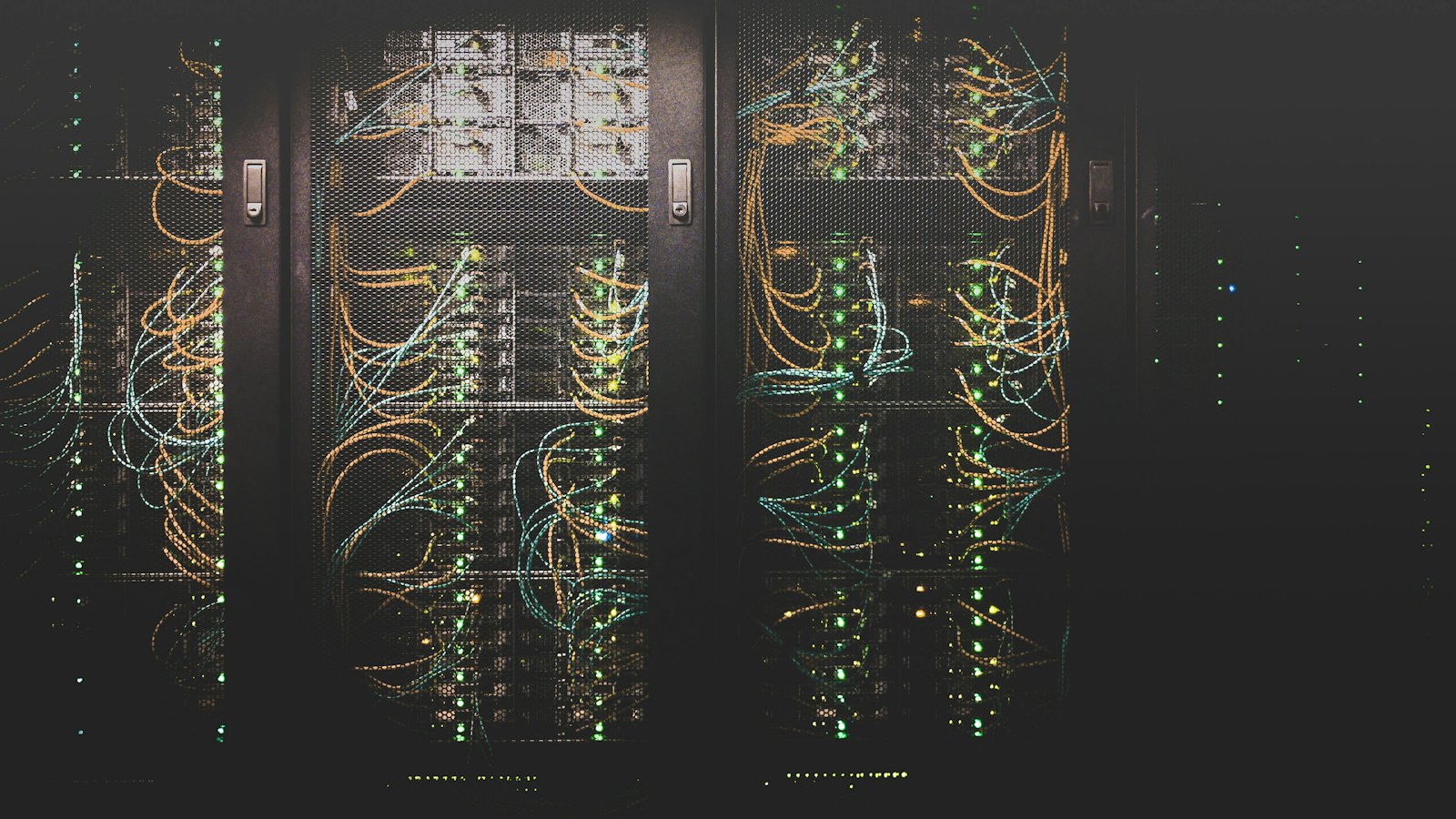 Server racks in a data hall, seen through perforated cabinet doors.